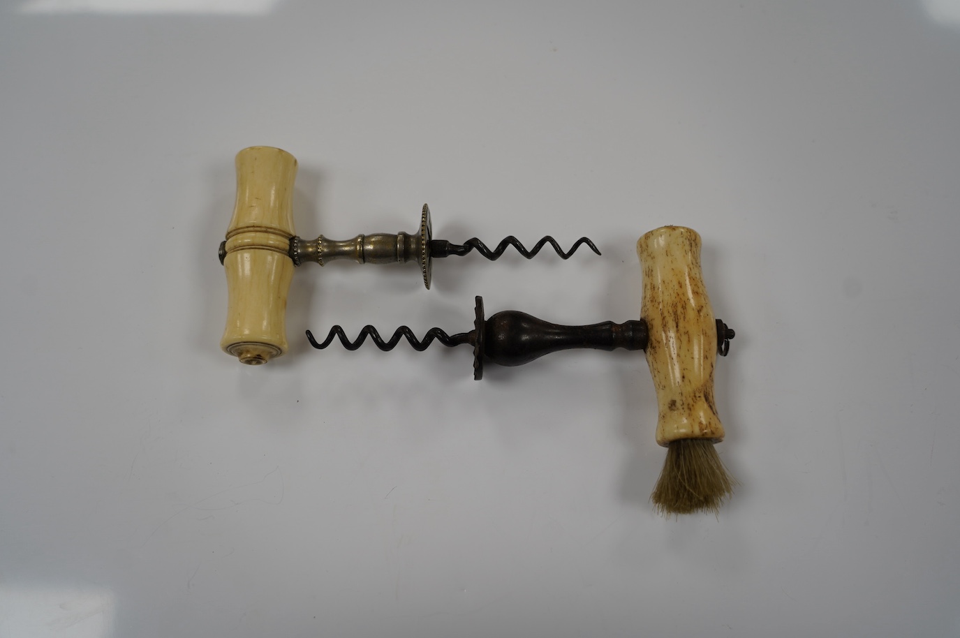 Two early 19th century bone handled corkscrews, one in steel with brush, the other in brass. Condition - good, brass example was silvered, small vacant hole to one end of the handle, no loop or ring